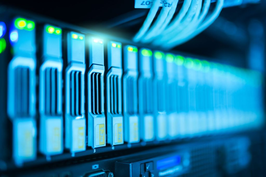 A long receding row of rack-mounted servers lit in deep blue, status LEDs glowing green along the front panels